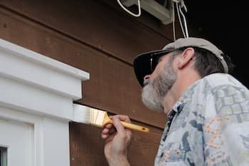 man painting exterior trim on house